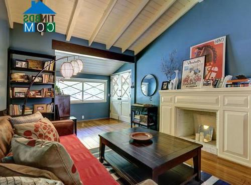 Tường màu xanh và tấm lót sofa màu đỏ làm phòng khách càng nổi bật