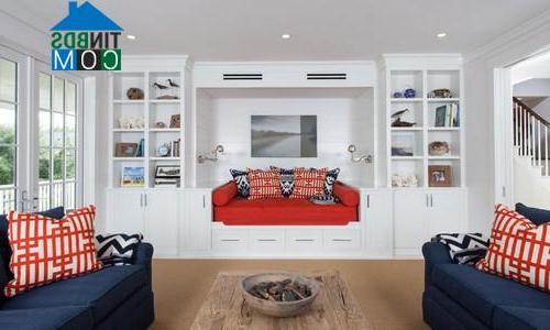 Ghế sofa xanh hải quân, đỏ, kết hợp họa tiết gối, tủ tường màu trắng giúp phòng khách này cá tính hơn