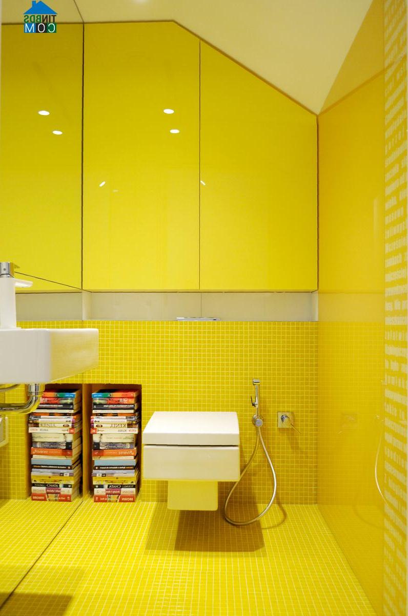 Phòng tắm màu vàng rực với một kệ sách nhỏ như điểm trang trí nổi bật