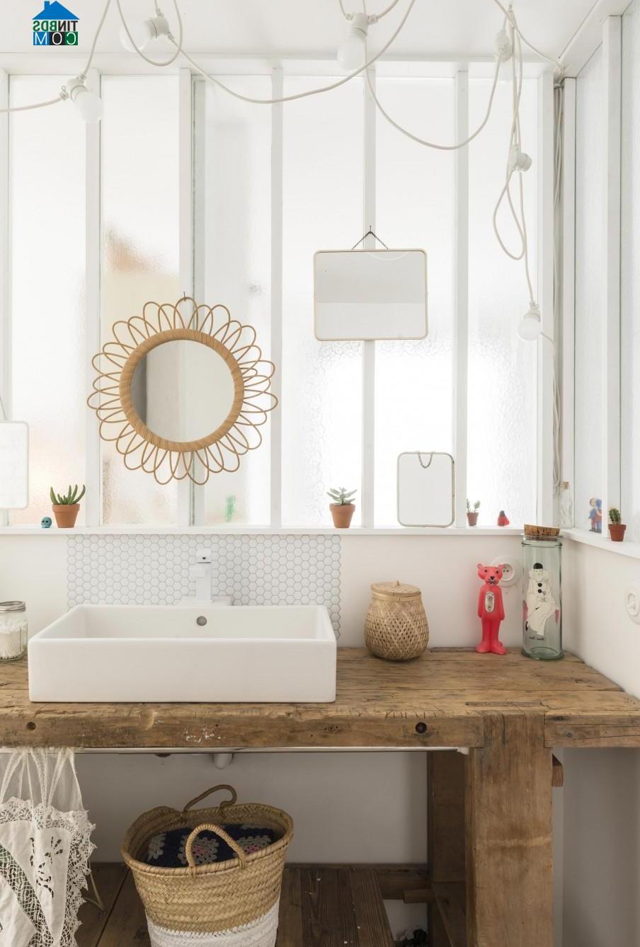 Phòng tắm dễ thương với viền gương bằng mây, bệ bồn rửa bằng gỗ