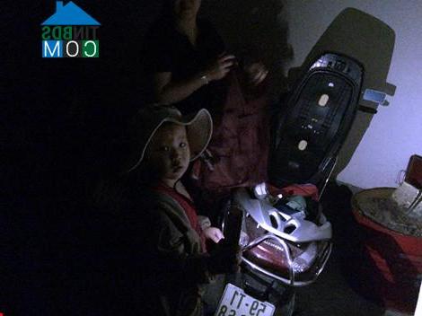 Một em nhỏ cầm đèn để mẹ cất đồ tại tầng hầm để xe chung cư